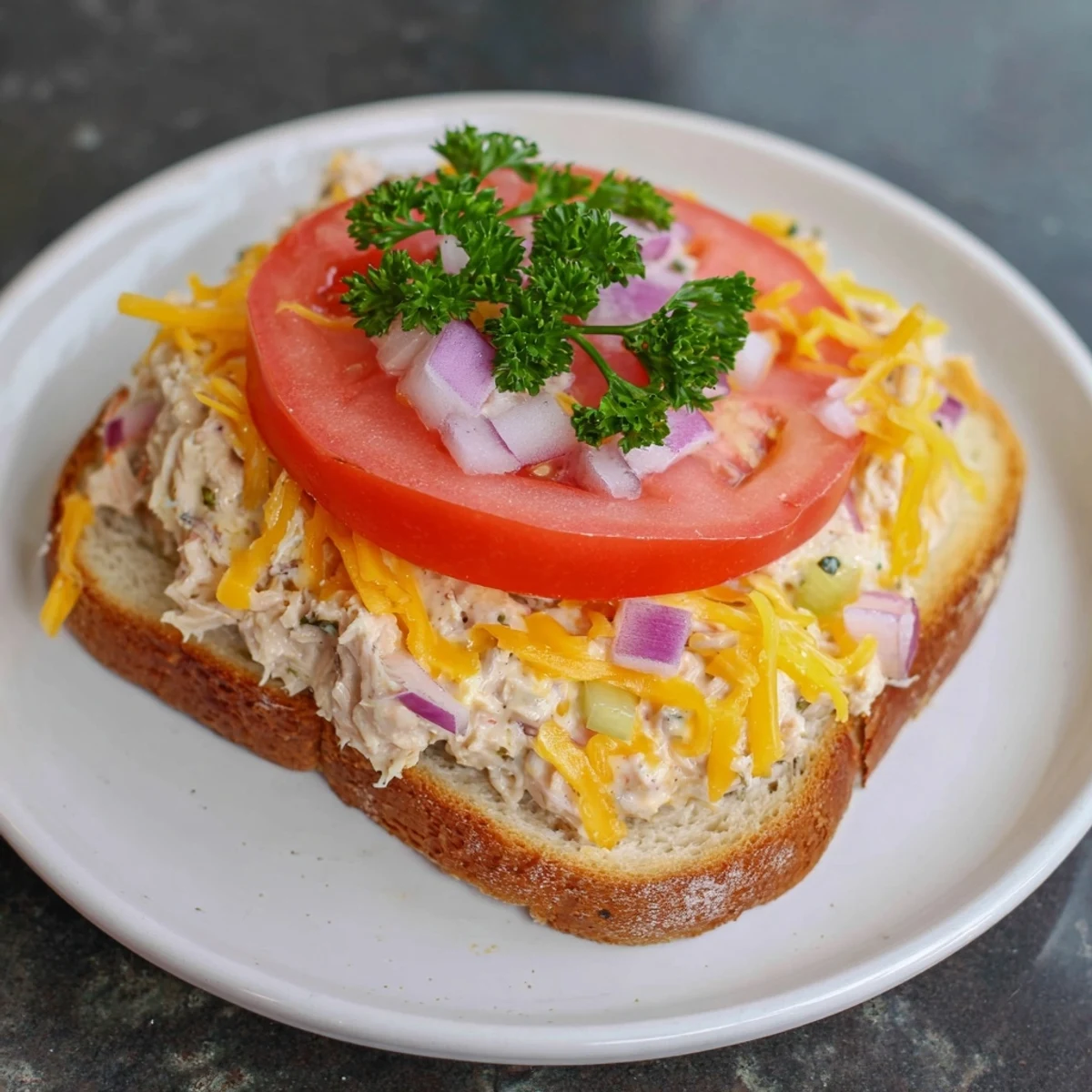 Close-up of a Tuna Melt, showing creamy tuna salad under melted cheese, perfect for a quick lunch.