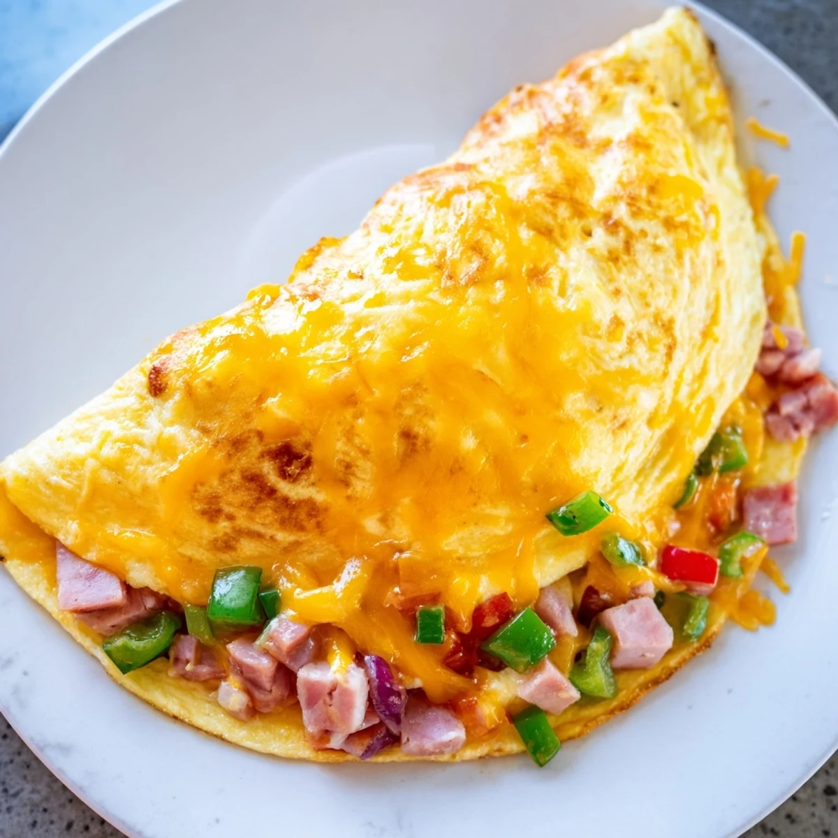 Fluffy, golden Denver Omelet, filled with savory ham, colorful peppers, and melted cheddar for breakfast.