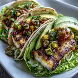 Fresh grilled fish tacos nestled in crisp lettuce shells and topped with a colorful mango salsa — a healthy, gluten-free Mexican-inspired meal.