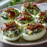 Bright green spinach and herb filling in classic deviled eggs, topped with crispy ham for a playful twist.
