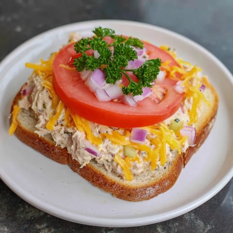 Close-up of a Tuna Melt, showing creamy tuna salad under melted cheese, perfect for a quick lunch.