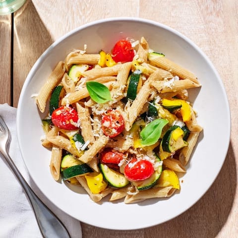 Garden Veggie Pasta served in a white bowl, garnished with basil and lemon zest, ready to enjoy with a crisp white wine.