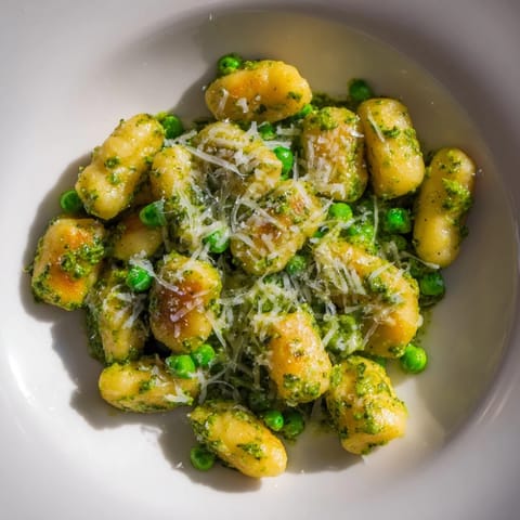A rustic white serving bowl holds the fragrant Pesto Pea Gnocchi Skillet garnished with fresh basil and grated Parmesan.  