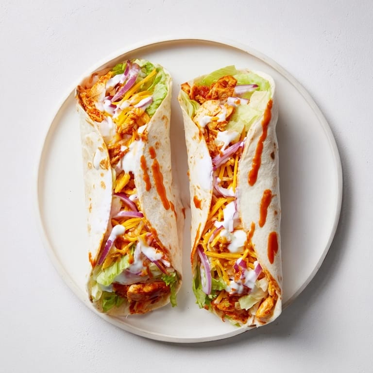 Golden-brown Buffalo Ranch Chicken Wrap sliced in half, revealing layers of spicy chicken, crunchy lettuce, and melted cheese inside a soft tortilla.
