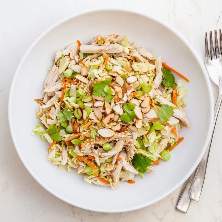 Serve this colorful Crunchy Ramen Chicken Salad garnished with scallions and sesame seeds for a crowd-pleasing potluck side dish.