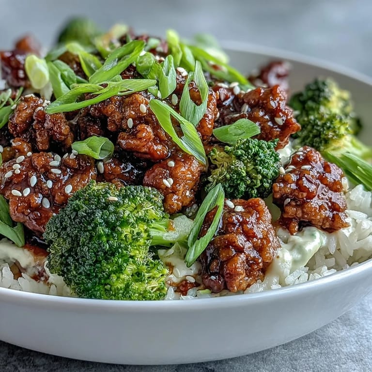 Savory Sweet and Spicy Turkey Broccoli Bowls ready to eat, garnished with fresh green onions and sesame seeds beside chopsticks on a wooden table.