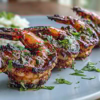 Jerk seasoning shrimp skewers sizzling on the grill, served over creamy coconut rice with fresh lime wedges and cilantro for a vibrant, tropical meal.  